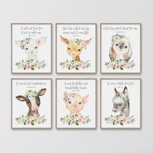 May include: Set of six framed watercolor prints featuring adorable animal portraits, each adorned with a floral crown and a biblical quote. The animals include a lamb, deer, bunny, cow, pig, and donkey. The frames are a light brown color.