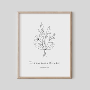Puede incluir: Impresión enmarcada con un dibujo lineal minimalista en blanco y negro de un ramo floral. El texto dice "She is more precious than rubies" y "PROVERBS 3:15". El marco es de color marrón claro. Un diseño simple y elegante.