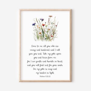May include: A framed print featuring a watercolor illustration of wildflowers in shades of red, blue, and white. The print includes the text "Come to me all you who are weary and burdened..." from Matthew 11:28-30.