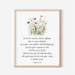 May include: A framed print featuring a watercolor floral arrangement in the upper center. The print includes the text "Do not be anxious about anything...Philippians 4:6-7" in a black, elegant font. The frame is a light wood color.