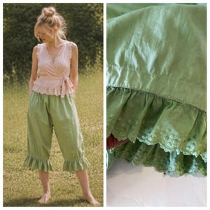 May include: A light pink wrap top with lace trim and a matching tie, paired with light green capri pants featuring ruffled hems. The pants are knee-length and made of a soft fabric, perfect for a casual, feminine look.