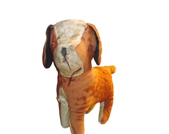 Puede incluir: Un juguete de peluche vintage con forma de perro, hecho de tela marrón y blanca. El perro tiene orejas de fieltro negro y una cara cosida.