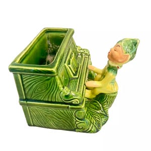 May include: Green ceramic planter shaped like a piano with a small elf figurine playing the keys.