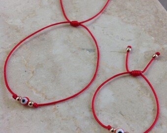 May include: Two red string bracelets with gold beads and a blue evil eye charm. The bracelets are adjustable and can be tied to fit any wrist.