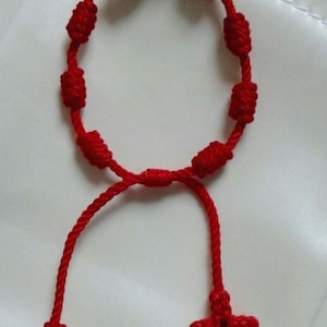 Pulsera roja para protección ajustable para bebés. Con extremo tejido de cruz.