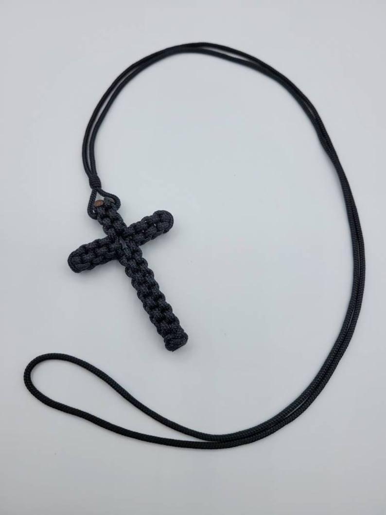 Puede incluir: Un collar de cord&oacute;n negro anudado con un colgante de cruz negra anudada.