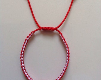 Könnte beinhalten: Rotes und weißes Armband aus Schnur mit einem blauen und weißen bösen Augen-Anhänger.