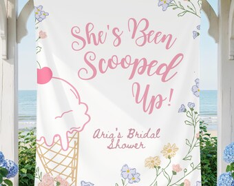 May include: A white banner with the text "She's Been Scooped Up!" in pink script, with an ice cream cone illustration. The banner is decorated with floral accents and the text "Aria's Bridal Shower".