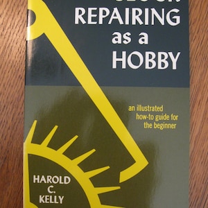May include: A book titled "CLOCK REPAIRING as a HOBBY" with a yellow gear and a yellow clock hand design on the cover. The author's name, Harold C. Kelly, is also visible. The book is an illustrated how-to guide for beginners.