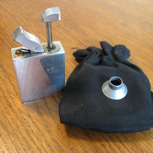 May include: A silver metal lighter with a lever and a small metal funnel in a black cloth bag.