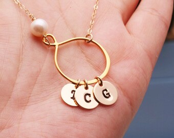 Puede incluir: Collar de oro con un dije de perla y tres dijes con iniciales. Las iniciales son I, C y G.