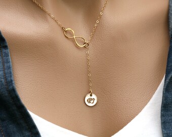 Puede incluir: Un collar de oro infinito con un pequeño colgante redondo con las iniciales "EJ".