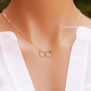 May include: A gold chain necklace with two interlocking circles as a pendant.