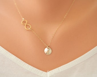 Puede incluir: Un collar de oro con un dije de símbolo de infinito y un pequeño dije redondo con la letra "S" en él.