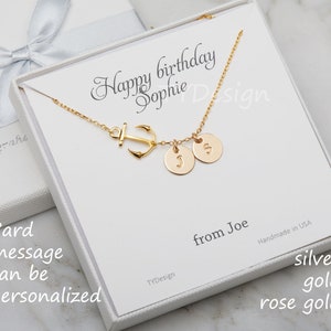 May include: A gold-colored necklace with an anchor charm and two round pendants, each with a letter. The necklace is presented in a white gift box with the text "Happy birthday Sophie". The card message can be personalized.