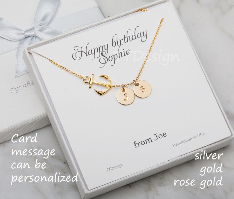 May include: A gold-colored necklace with an anchor charm and two round pendants, each with a letter. The necklace is presented in a white gift box with the text "Happy birthday Sophie". The card message can be personalized.