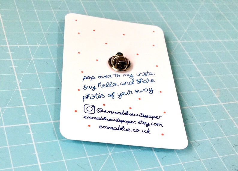 May include: A white card with red dots and blue text. The text reads "pop over to my insta. &bull; say hello, and share photos of your swag" and includes the social media handle "@emmabluecutspaper", website "emmabluecutspaper.etsy.com", and website "emmablue.co.uk".