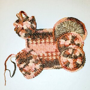 May include: A set of three crocheted pot holders in shades of brown, pink, and beige. The pot holders are shaped like a flower, a heart, and a square.