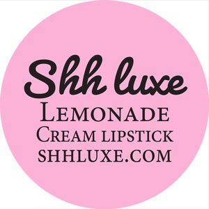May include: Pink circle with black text that reads "Shh luxe LEMONADE CREAM LIPSTICK SHHLUXE.COM"