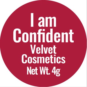 May include: A red circle with white text that reads "I am Confident Velvet Cosmetics Net Wt. 4g".