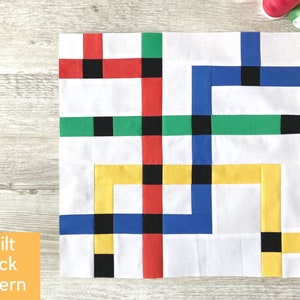 Puede incluir: Un patrón de bloque de colcha con un fondo blanco y formas geométricas de colores. Las formas son rojas, verdes, azules, amarillas y negras.