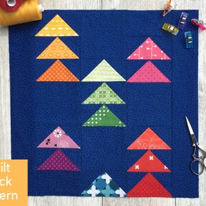 May include: A quilt block pattern with a blue background and colorful triangles arranged in a geometric pattern. The text "Quilt Block Pattern" is visible in the lower left corner.