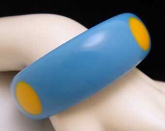 May include: A blue plastic bangle bracelet with two yellow circles.