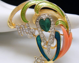 May include: Gold-tone metal Virgo zodiac sign brooch with green, teal, and coral enamel accents. The brooch features a central green heart-shaped stone, clear rhinestones, and a star. The word "Virgo" is spelled out in rhinestones.