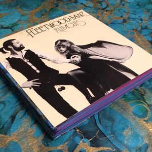 May include: A vintage vinyl record album cover featuring Fleetwood Mac's "Rumours" album. The cover art shows two people in black and white, with the woman holding a small object in her hand.