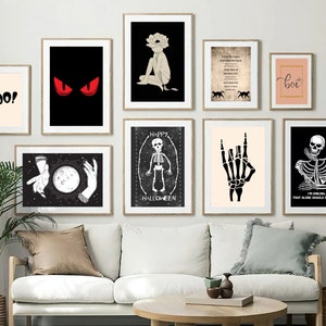 May include: A collection of framed art prints with a Halloween and gothic theme. The prints feature images of a skeleton, a hand making a rock on gesture, and the word "boo!". Other prints include a figure with a flower head and a pair of red eyes.