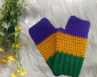 May include: Purple, gold, and green crocheted fingerless gloves on a white fluffy surface.