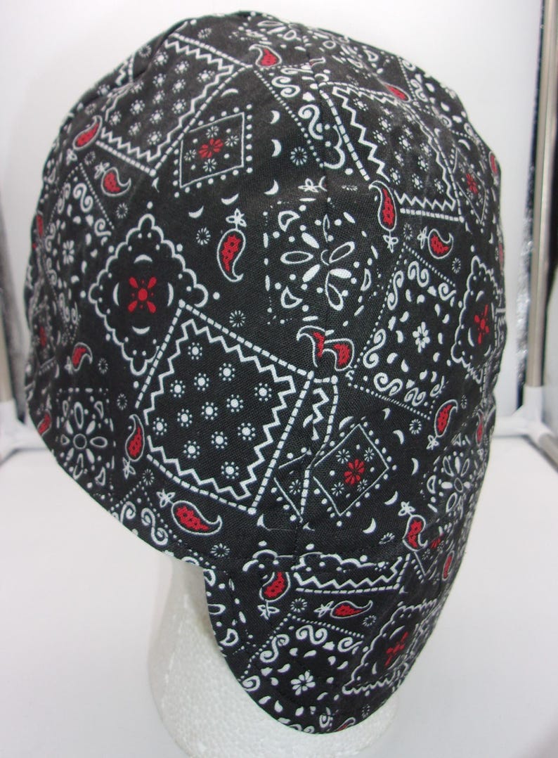 May include: Black and white bandana pattern welding cap with red accents. The cap is made of a durable fabric and is designed to protect the wearer's head and neck from sparks and heat.