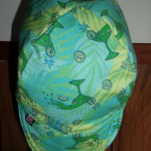 May include: A green and blue patterned welding cap with the text "It's 5 O'Clock Somewhere" on the side.