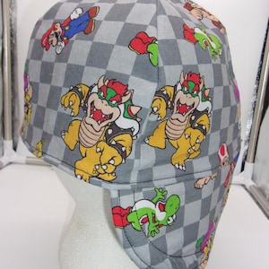 May include: A gray and white checkered fabric welding cap with a variety of Mario characters, including Mario, Luigi, Bowser, and Yoshi.