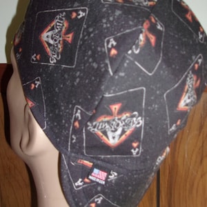 May include: Black welding cap with a pattern of playing cards, including aces of spades and hearts. The cap has a small American flag patch with the text "Made in USA".