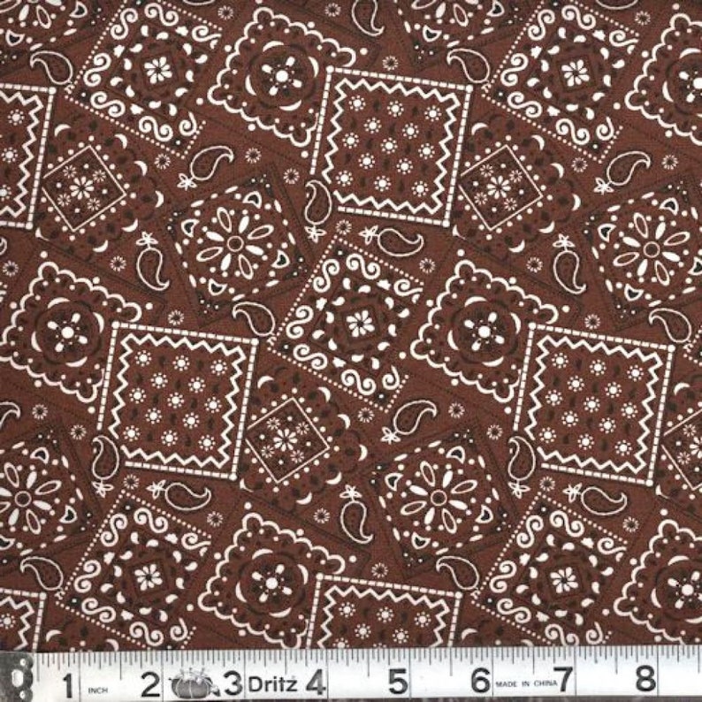 May include: Brown fabric with a white bandana print. The fabric features a repeating pattern of paisley and square bandana designs.