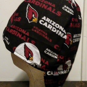 May include: A black and red baseball cap with a white and red Arizona Cardinals logo. The cap has a white brim and a red and white strap.