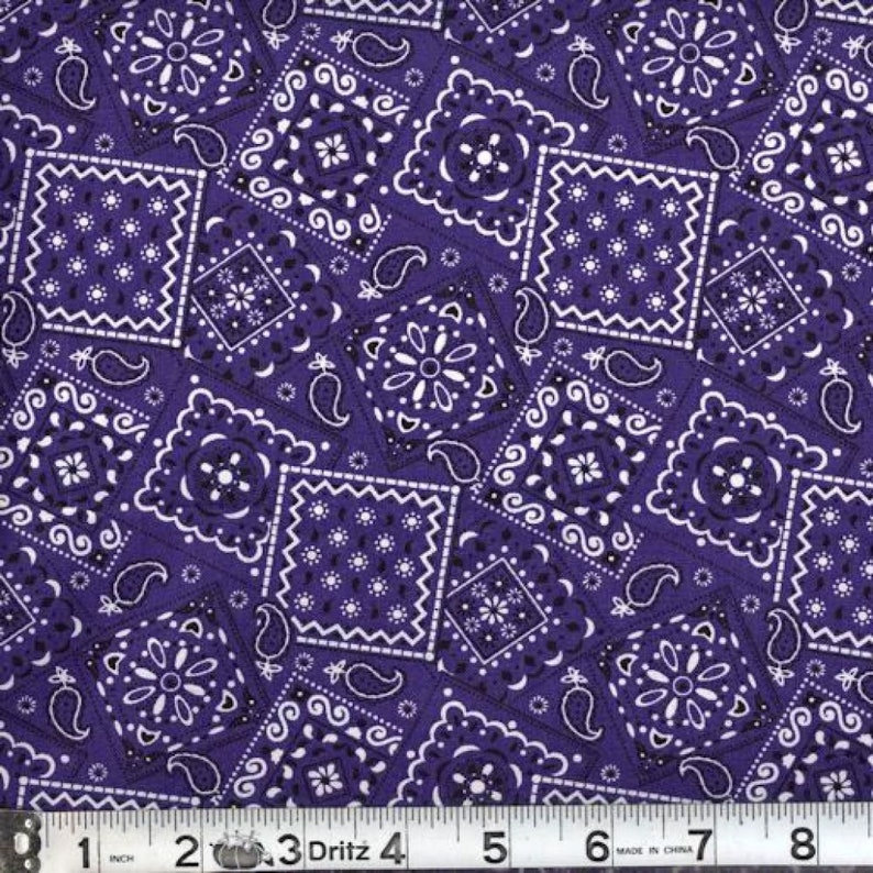 May include: Purple fabric with a white bandana print. The fabric is patterned with various sizes of squares and paisley shapes.