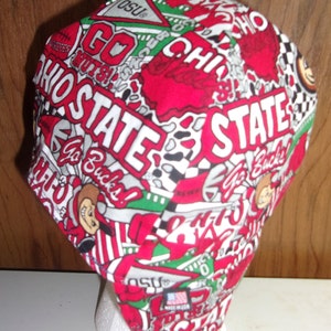 May include: A fabric cap featuring a repeating pattern of Ohio State University graphics in red, white, and green. The design includes the text OHIO STATE, Go Bucks, and OSU pennants. A small rectangular tag on the side reads MADE IN USA.