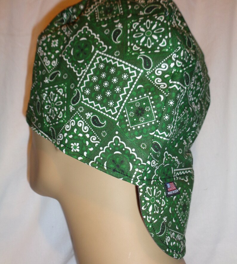 May include: Green bandana-style welding cap with a white paisley pattern. The cap has a long flap that covers the neck and shoulders. Made in the USA.