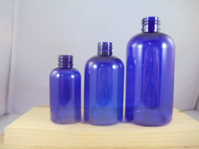 Puede incluir: Tres botellas de pl&aacute;stico azules de diferentes tama&ntilde;os. Las botellas son transparentes y tienen un ligero tono azul. Todas est&aacute;n de pie sobre una superficie de madera.