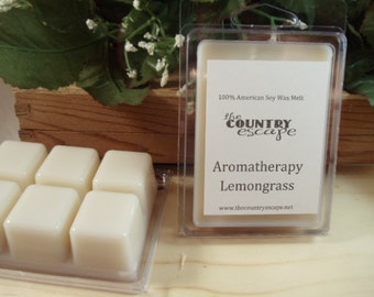 May include: Six white soy wax melts in a clear plastic container. The wax melts are square shaped and have a label that reads "100% American Soy Wax Melt", "the COUNTRY escape", "Aromatherapy Lemongrass", and "www.thecountryescape.net".