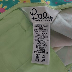 May include: A light green garment featuring a white fabric care label with the text Lilly Pulitzer. The label includes washing instructions: machine wash cold, gentle cycle, non-chlorine bleach, tumble dry low, and warm iron on reverse if needed.