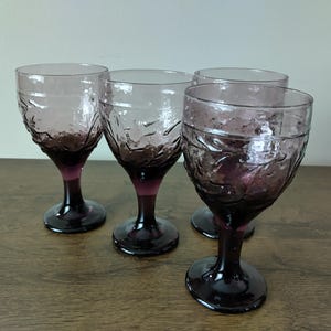 May include: Set of four purple glass wine goblets with a textured design.