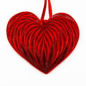 May include: A red paper quilled heart ornament with a red ribbon for hanging.
