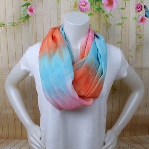 May include: A soft, lightweight infinity scarf in a tie-dye pattern with shades of pink, blue, and orange.