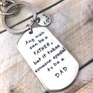 May include: Silver keychain with a tag that reads "Any man can be a FATHER, but it takes someone special to be a DAD".