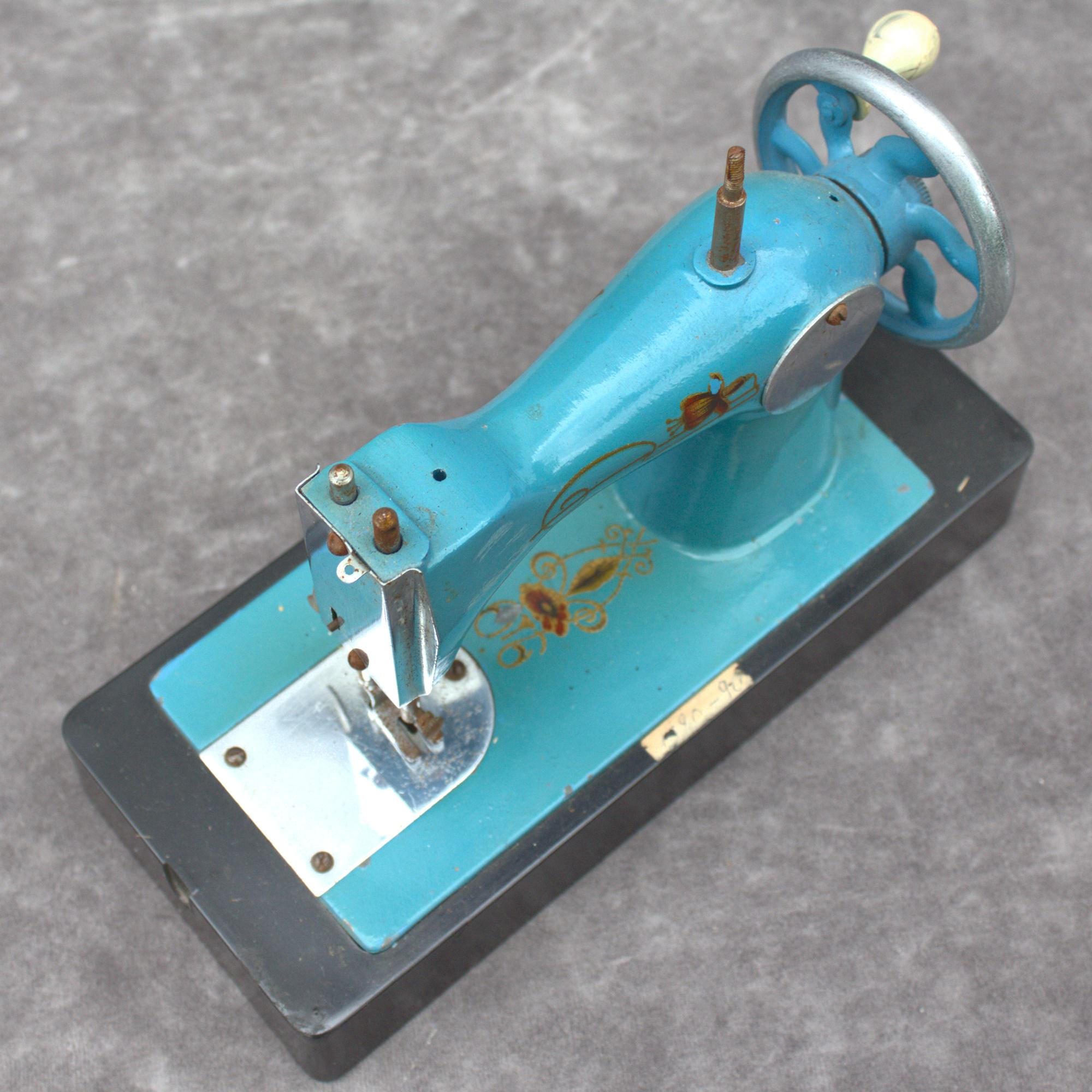 本物のヴィンテージ金属製子供用ミシン、ライトブルー。装飾的な花柄が