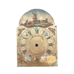 May include: Antique clock face with a painted landscape scene featuring a windmill and houses. The face has Roman numerals, floral accents, and the name "JAN KIN" and "STARLE". The clock face is aged with visible wear.
