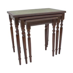 Può includere: Un set di tre tavolini a incastro realizzati in legno marrone scuro. Ogni tavolo presenta un piano rettangolare con un inserto in pelle verde e quattro gambe sottili e tornite. I tavoli sono impilati insieme in una disposizione a gradini.